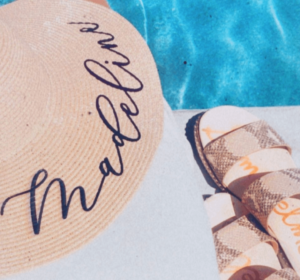 Image of a sun hat and a pair of Sam Edelman Sandals next to a pool