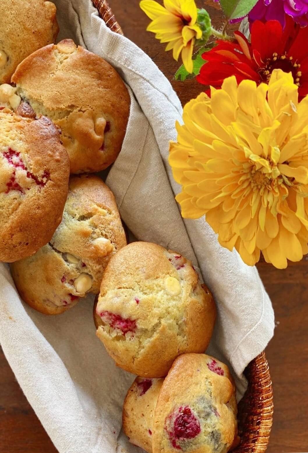 Close up of muffins in a basket next to flowers