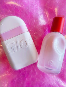 Image of The You Glossier Perfume and Another Glossier Product lying on its Pink Packaging