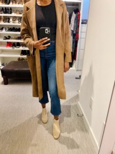 Image of Sara taking a picture in the mirror in a fall jacket, jeans top and booties