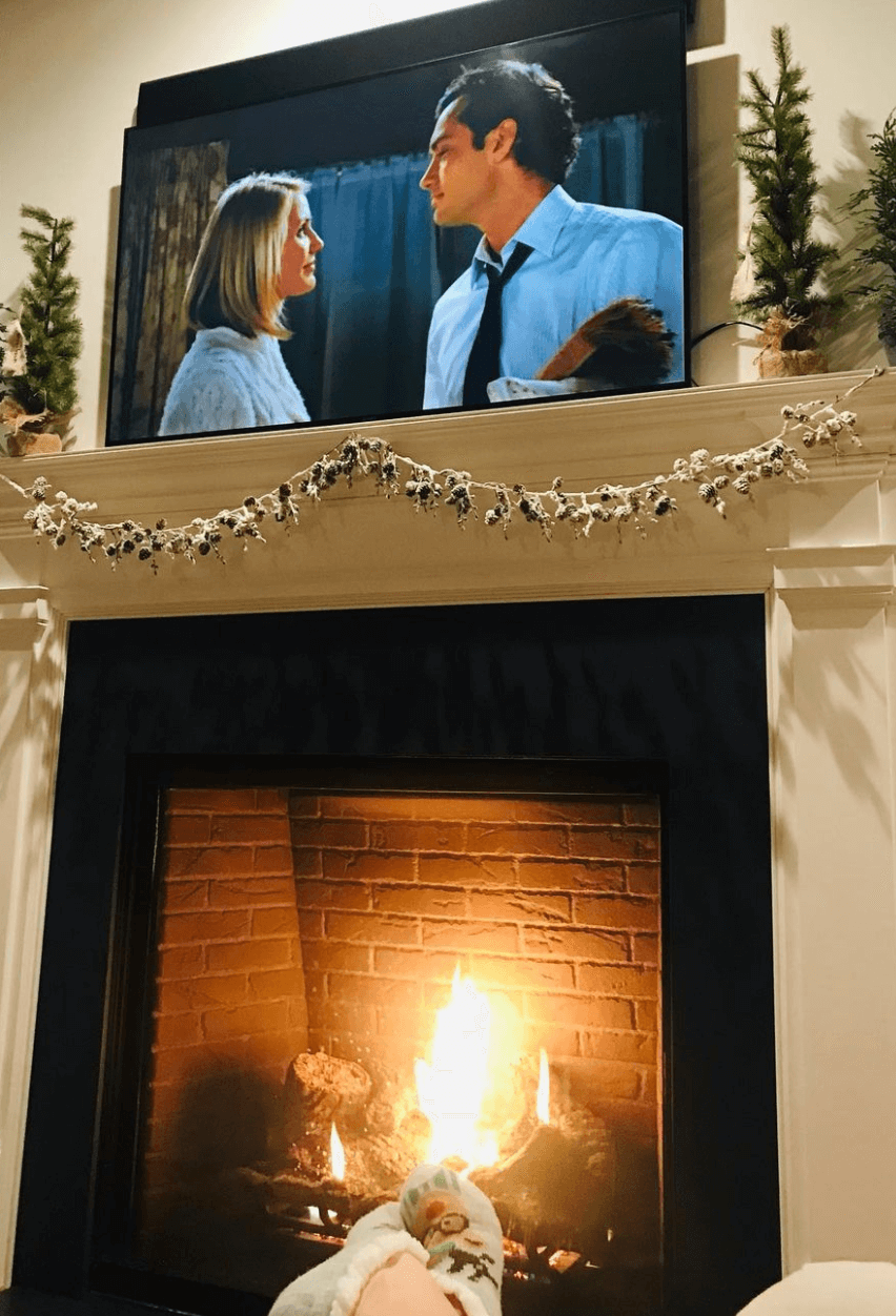 Image of a fireplace with the Holiday playing on the tv