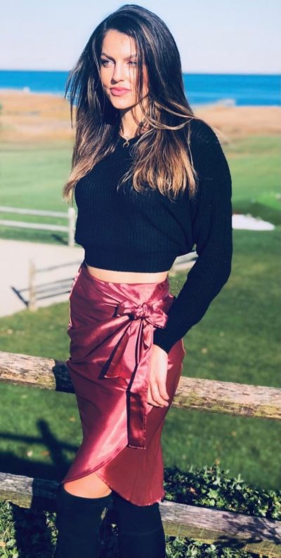 Image of Maddie wearing a pink satin skirt and black sweater 