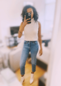 Image of sara in sleeveless sweater top and jeans 